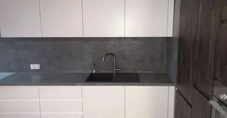 Nowoczesna kuchnia po remoncie z eleganckimi wykończeniami wnętrz, stworzona przez profesjonalną firmę remontową. Szare blaty i białe szafki tworzą minimalistyczny design.