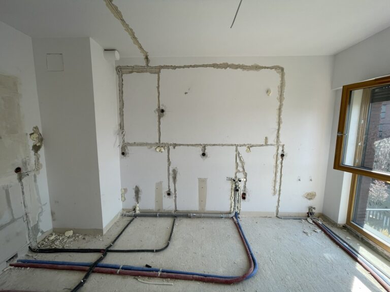 Remontowane wnętrze z usuniętymi ścianami i widocznymi instalacjami, przygotowane do dalszych wykończeń. Firma remontowa zajmuje się kompleksową modernizacją przestrzeni.