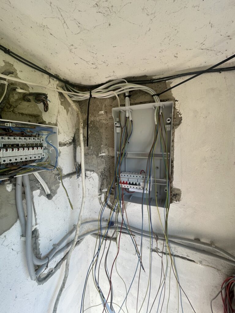 Zabudowa instalacji elektrycznej w trakcie remontu, pokazująca rozdzielnicę oraz kable. Profesjonalne wykończenia wnętrz przez firmę remontową.