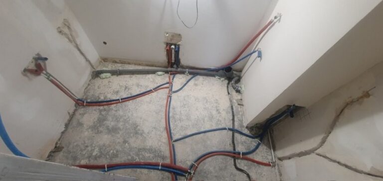 Prace remontowe w nowoczesnym wnętrzu: widok na przygotowanie instalacji wodnej i elektrycznej w pomieszczeniu, wykonane przez profesjonalną firmę remontową.