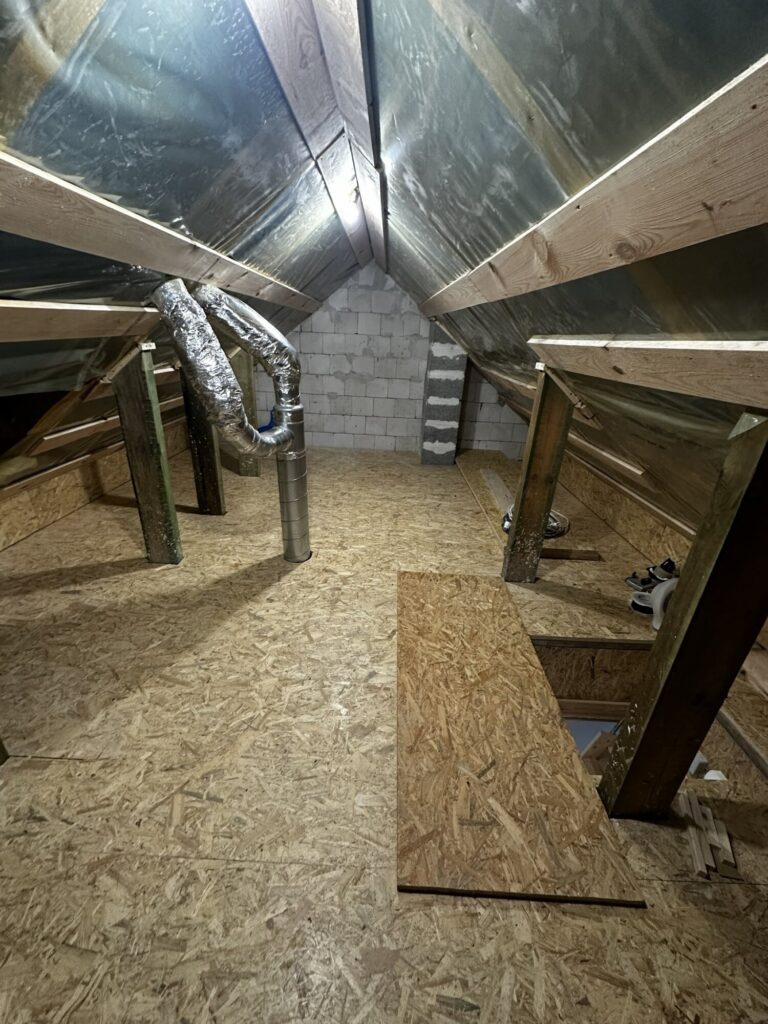 Wykończona poddaszowa przestrzeń przygotowana do remontu, ukazująca drewniane belki oraz elementy wentylacji, idealna dla firmy remontowej specjalizującej się w modernizacji wnętrz.