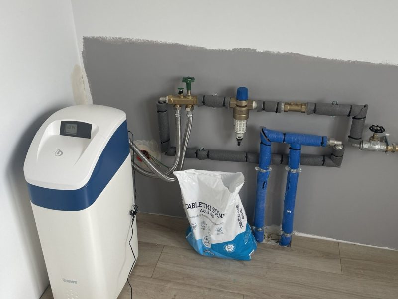 Instalacja hydrauliczna w trakcie remontu wnętrza, z widocznym urządzeniem do uzdatniania wody. Profesjonalne wykończenie wnętrz przez firmę remontową.